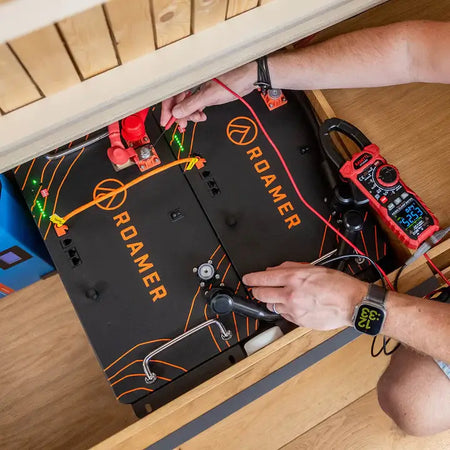 Two Roamer home batteries situated under the sofa in Roamer's Torsus campervan. Steve from Roamer checking their status.