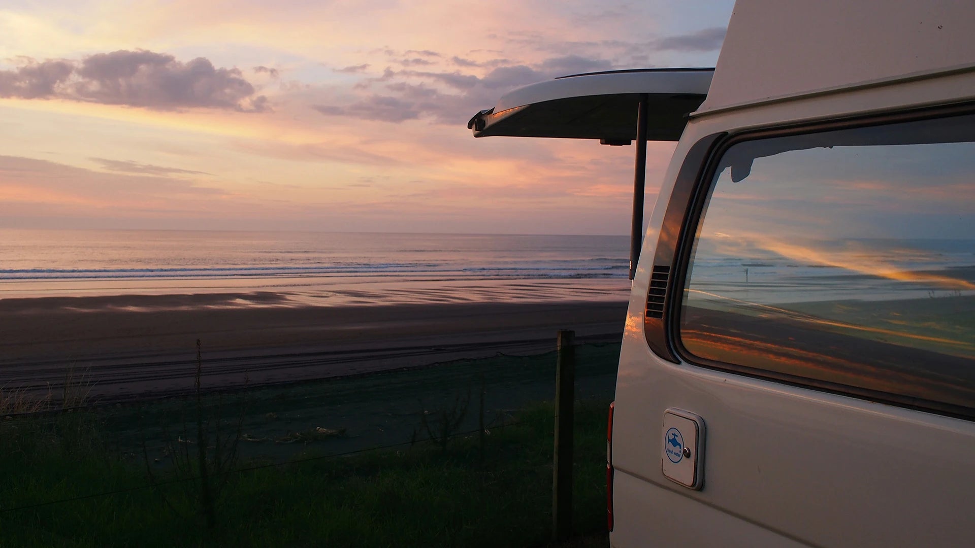 Campervan parked up along the beach front as the sun is setting.