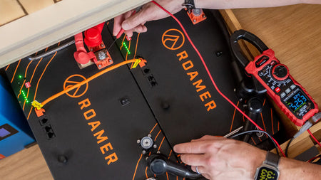 Two Roamer home batteries situated under the sofa in Roamer's Torsus campervan. Steve from Roamer checking their status.
