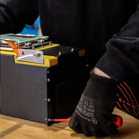 Simon from Roamer batteries unscrewing a Roamer battery in their warehouse.