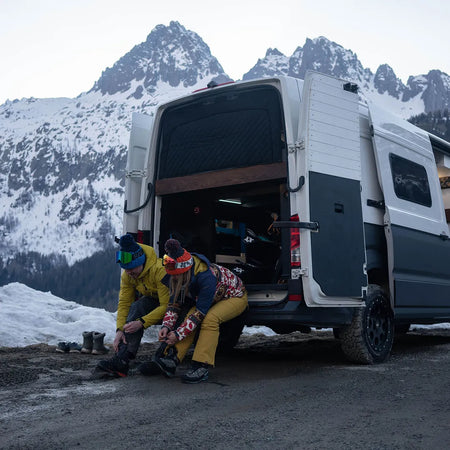 Kate and Steve from Roamer Batteries putting their ski boots on from the back of their campervan in Chamonix.