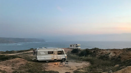 Two motorhomes parked next to a cliff edge looking over the sea.