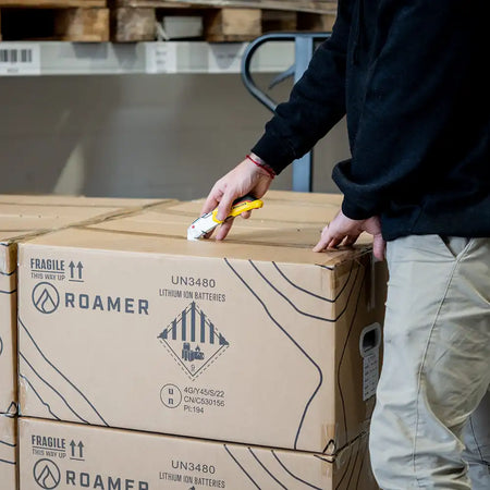 A Roamer team member opening up a Roamer branded box which they store their lithium batteries in.