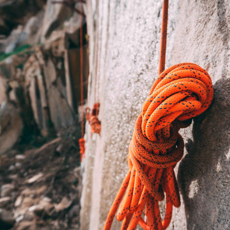 Climbing rope in a knot against a mountain - ready to be used by a professional climber.