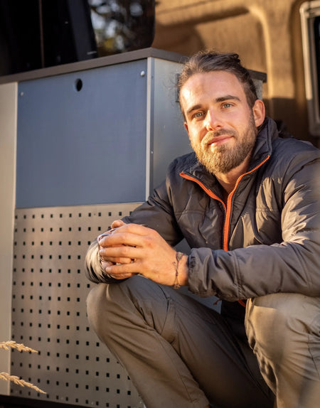 A young man sat in the back of a campervan.