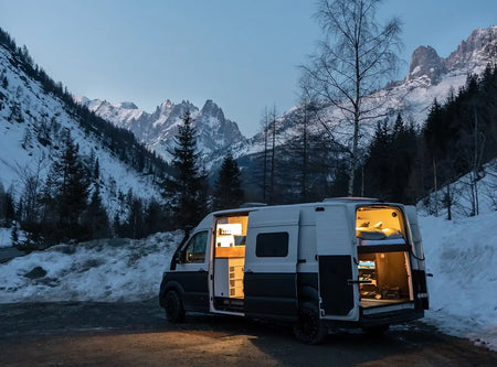 Roamer's campervan Chewie lit up on a snowy night in Chamonix.